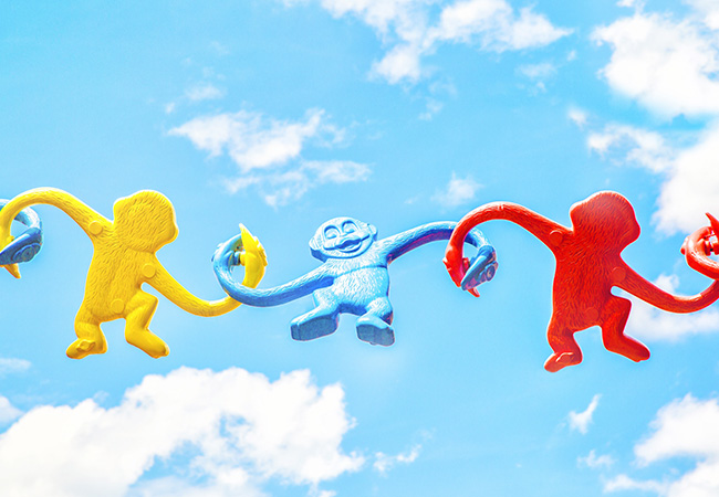Three monkey toys in red blue and yellow