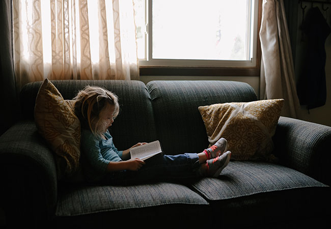 A girl reading a book on her sofa