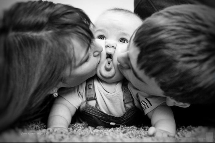 Parents kissing their baby