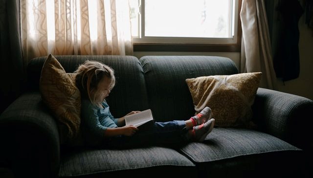 A girl reading her book on sofa bed